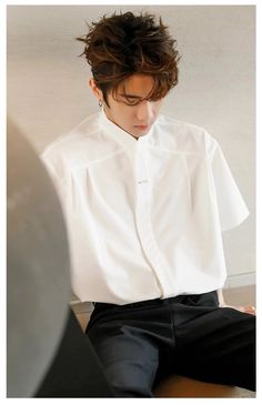 a man sitting on top of a wooden table wearing a white shirt and black pants