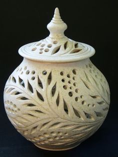 a white vase with an intricate design on the top and bottom, sitting against a black background