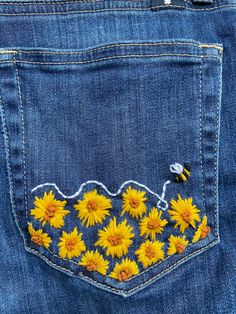 the back pocket of a pair of jeans with embroidered sunflowers on it and a bee