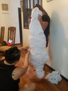 two women in black shirts and one is wrapping up a large white object