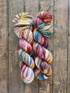 several skeins of multicolored yarn hanging on a wooden wall