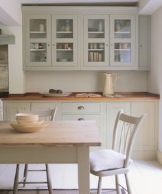 a table and chairs in a room with white walls, cupboards and counter tops