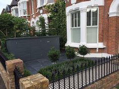 a brick house with white windows and black wrought iron fence