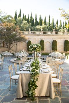 an outdoor dining area with tables and chairs set up for a formal function in the garden