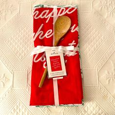 a wooden spoon sitting on top of a red towel next to a white and green napkin