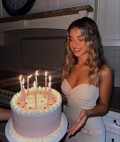 a woman standing in front of a cake with lit candles