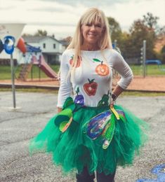 a woman wearing a green tutu skirt with pumpkins and leaves on the side