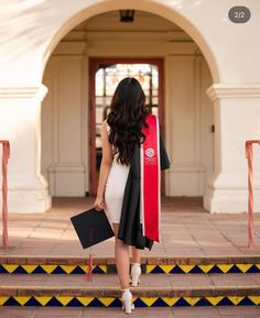 a woman walking up some steps wearing a graduation gown and holding a book in her hand