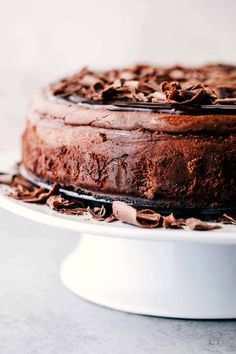 a chocolate cake sitting on top of a white platter covered in chocolate frosting