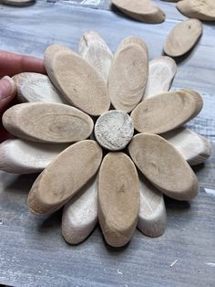 a hand holding a wooden flower on top of a table next to other wood pieces