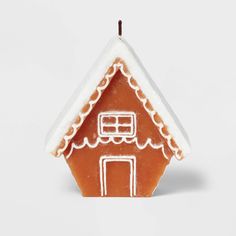 a ginger house with icing on the roof and snow on the roof, in front of a white background