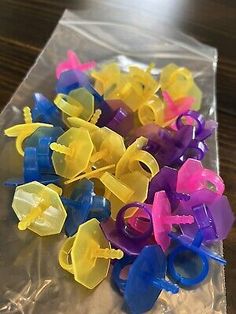 several different colored plastic clips in a package on a wooden table with a black surface