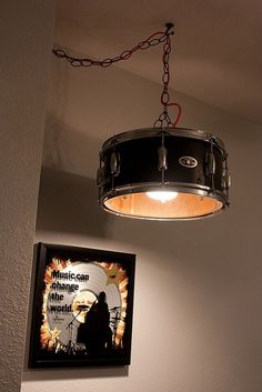 a drum light hanging from the ceiling in a room with a poster on the wall