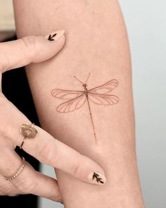 a woman's arm with a dragonfly tattoo on it