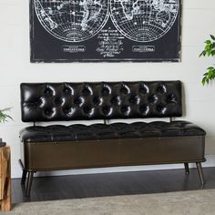 a black leather bench sitting in front of a wall with a map hanging on it