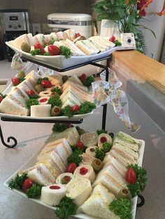 three tiered trays filled with sandwiches and vegetables