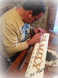 a man sitting at a table writing on a sign