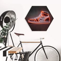 a bicycle parked next to a wall with a neon shoe sign on it's side