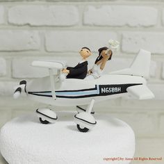 a wedding cake topper sitting on top of a small plane with a bride and groom in it