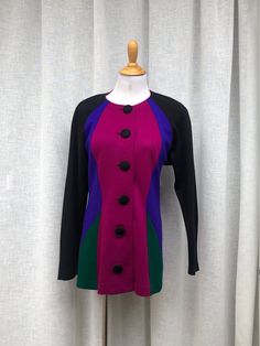 "For sale is a beautiful single breasted blazer by l.magnin in purple, fuchsia, green colors and black sleeves,  button down with big fabric wrapped black buttons, the shoulders are padded. 100% Acrylic.  Marked size 10 Good vintage condition!  Measurements (flat): shoulder to shoulder approx 14\" Armpit to armpit: 17\" sleeve length approx: 20\" Overall length: 28\"" Fitted Fall Outerwear With Color Block, Purple Long Sleeve Cardigan With Button Closure, Purple Long Sleeve Outerwear With Buttons, Purple Cardigan For Workwear In Fall, Purple Cardigan For Workwear, Fall Season, Purple Cardigan For Fall Workwear, Purple Cardigan For Work In Fall, Fitted Purple Cardigan With Buttons, Multicolor Formal Winter Blazer