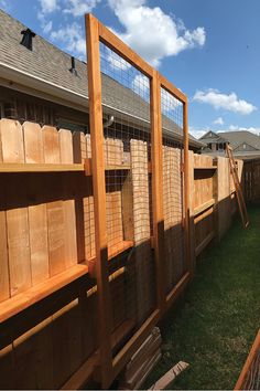 a fenced in backyard with wooden shelves and grass on the ground next to it