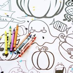 some crayons are laying on top of a coloring page with an image of a pumpkin