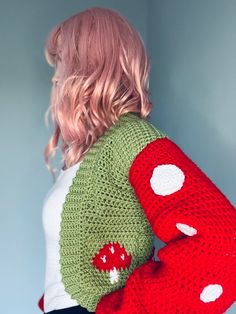 a woman wearing a red and green knitted sweater with white polka dots on the sleeves