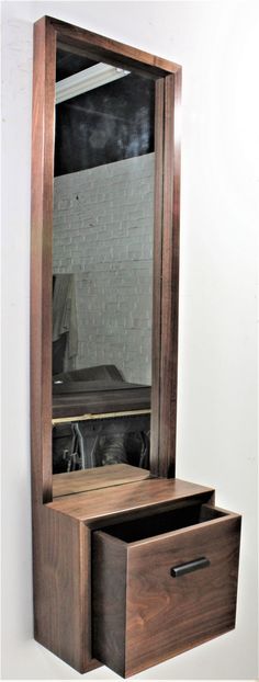 a wooden dresser with an open drawer underneath it and a mirror on the wall behind it