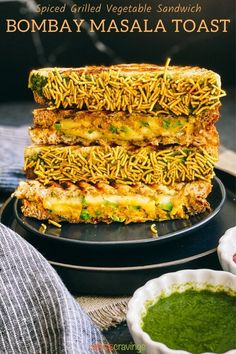 a stack of grilled vegetable sandwiches on top of a black plate with green sauce