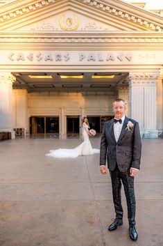 a man in a tuxedo standing outside the entrance to a building with a bride and groom