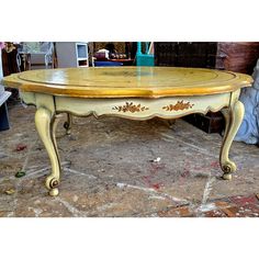 an old table is painted yellow and has ornate carvings on the top with gold leaf accents