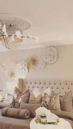 a large bed sitting under a chandelier next to a table with flowers on it