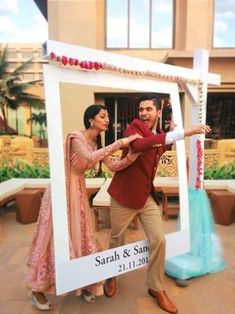 a man and woman standing in front of a photo frame