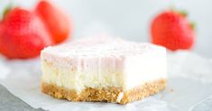 a piece of cheesecake with two strawberries in the background