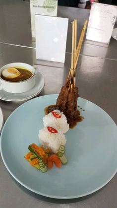 a blue plate topped with rice covered in meat and veggies next to chopsticks