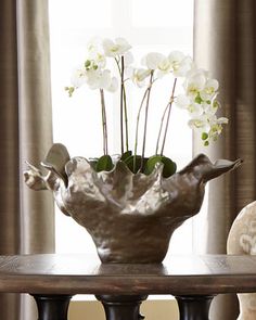 a vase filled with white flowers sitting on top of a table next to a teddy bear