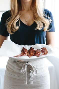 a woman holding a plate with bacon on it