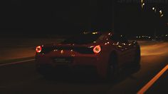 a red sports car driving down the road at night