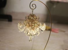 a gold chandelier with crystal drops on it's sides and a metal stand in the middle