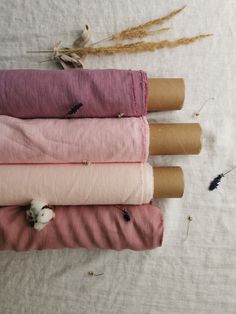 four different colored linens laid out on top of each other, with dried flowers in the background