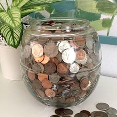 a glass jar filled with coins next to a potted plant