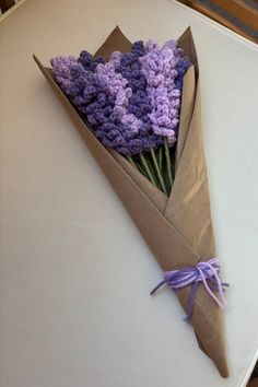 a bouquet of purple crocheted flowers wrapped in brown paper