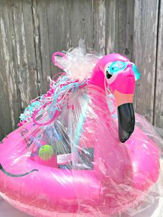 an inflatable pink flamingo float on top of a white table and wooden fence