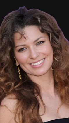 a woman with long brown hair smiling at the camera and wearing gold earrings on her head