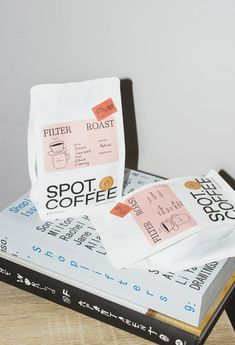 two bags of coffee sitting on top of each other next to a stack of books