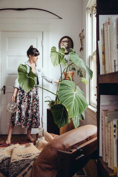 a woman standing next to a plant in a living room