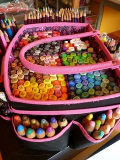 a pink case filled with lots of crayons and pencils on top of a counter