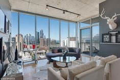 a living room filled with furniture and large windows overlooking a cityscape in the distance