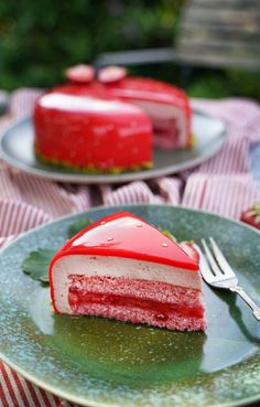 a piece of cake on a plate with a fork next to it and another slice in the background