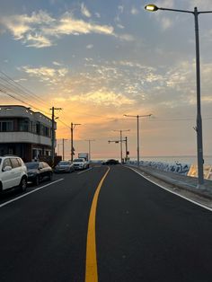 cars are parked on the side of an empty road near some buildings and street lights